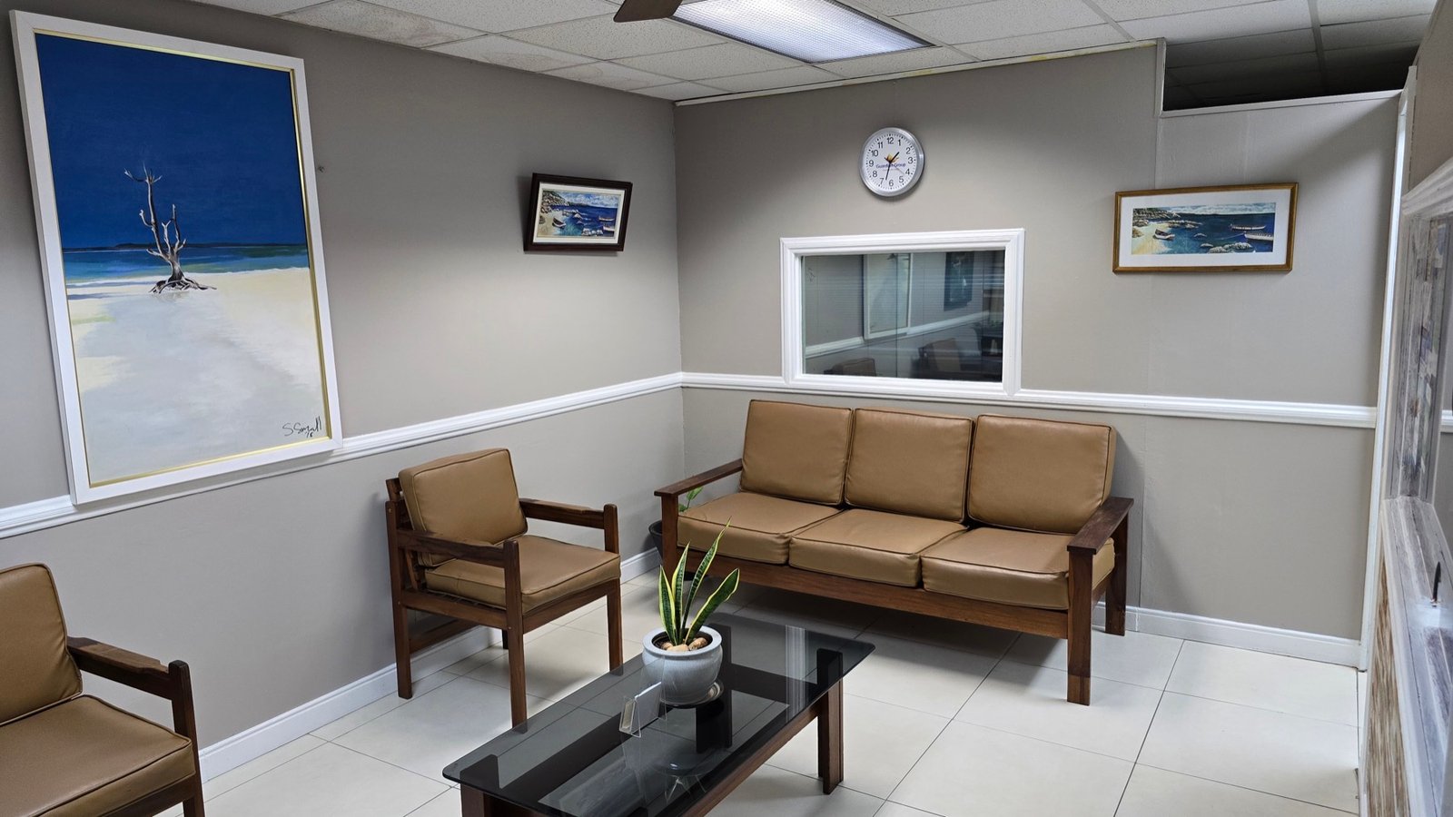 The waiting room at Oxford Dental Centre, with seating and framed Jamaican coastal paintings.
